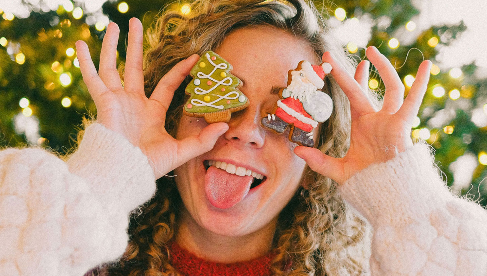Eine junge Frau im Weihnachtspulli hält sich Christbaumschmuck vor die Augen. Fotocredits: Anna Shvets, pexels