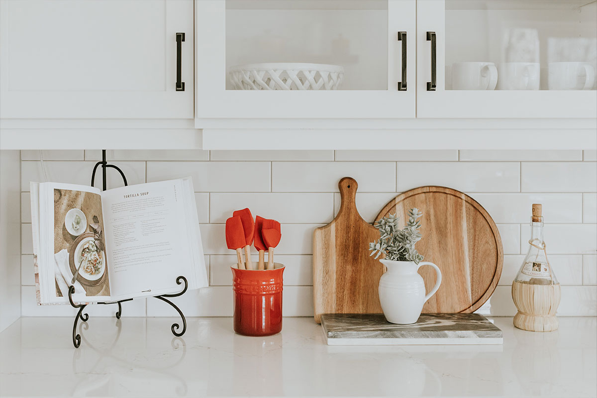 Das Foto zeigt eine weiße, blitzblank geputzte Küchenzeile mit weißen Oberschränken. Fotocredits gehen an Becca Tapert, unsplash