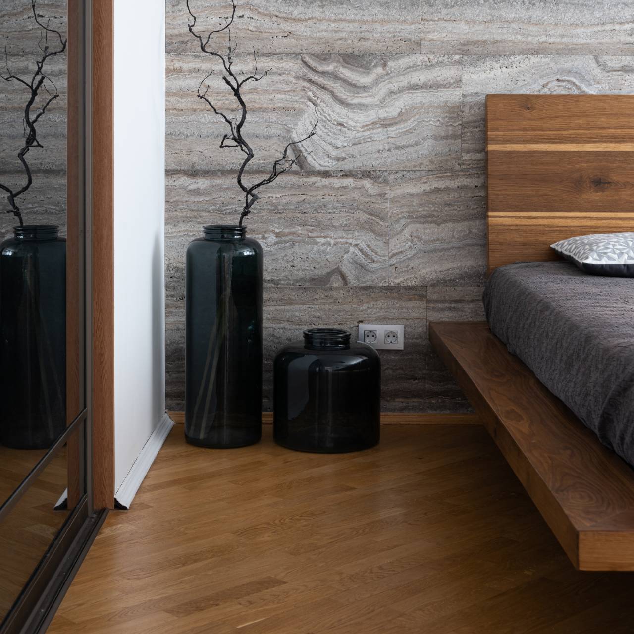 Ein helles Schlafzimmer im skandinavischen Design mit einem Holzfußboden mit hellem Fischgrätparkett