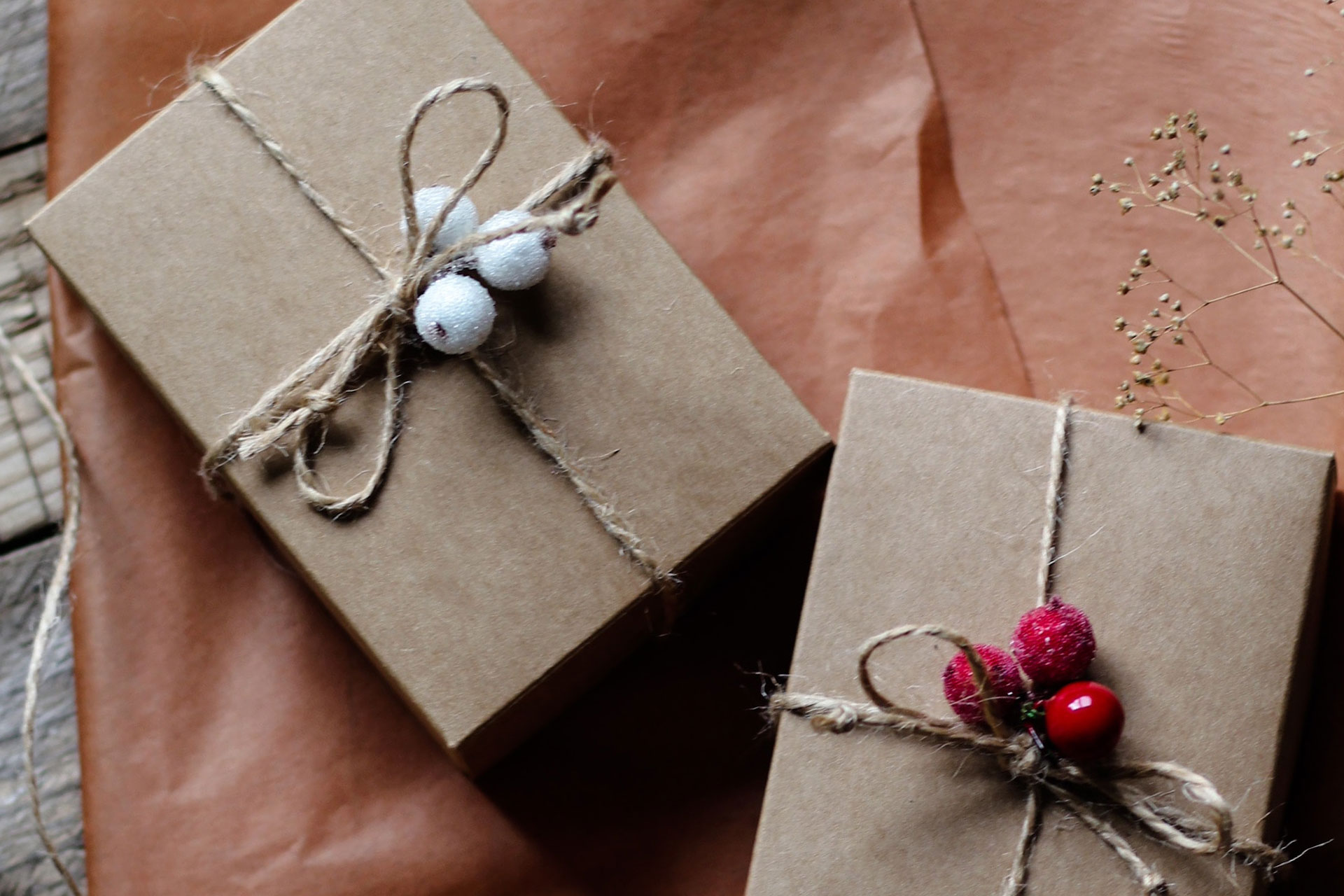 Zwei eingepackte Geschenke liegen auf einem altrosa-farbenen Geschenkpapier. Fotocredits: Olga Safronova, unsplash
