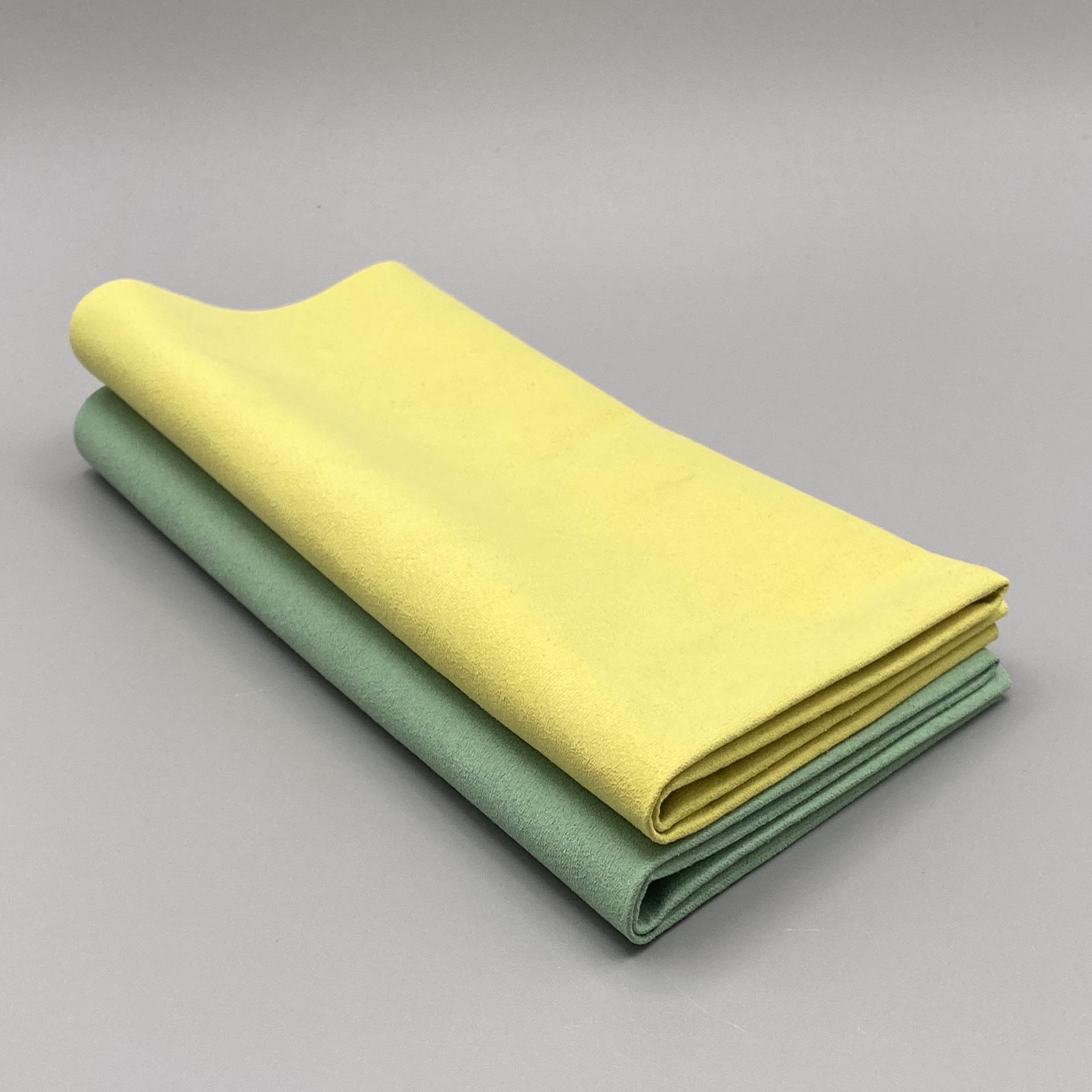 Zwei zweifach gefaltete Mikrofasertücher Premium in der farblichen Reihenfolge Grün und Gelb liegen übereinander