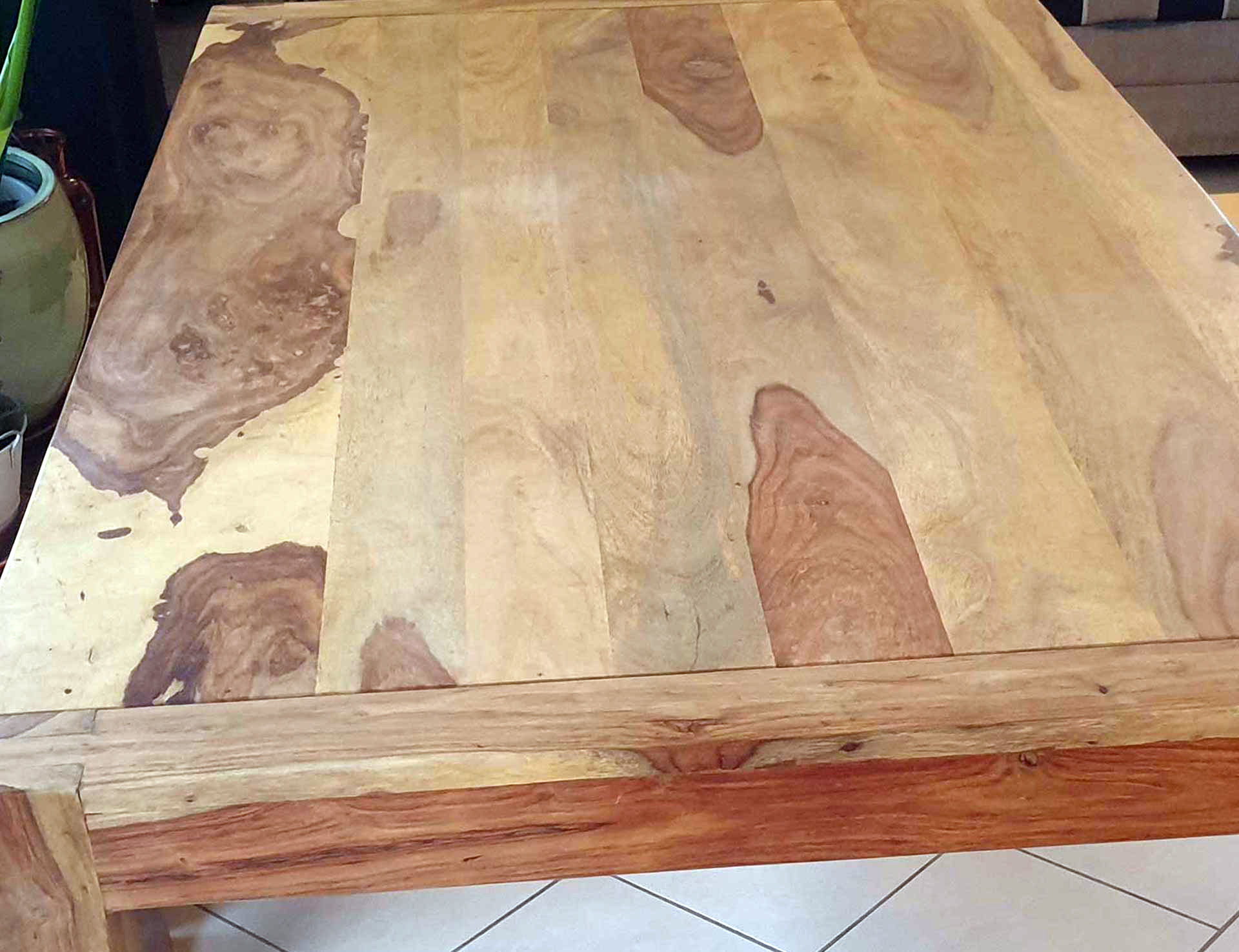 Das Bild zeigt einen Holztisch aus Sheesham-Holz, der deutlich verblasst ist
